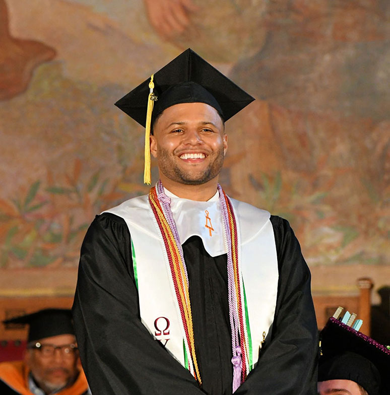 College student standing at his graduation in a cap and gown.