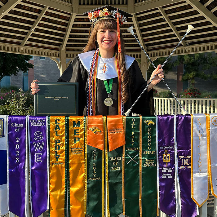 Female student posing and smiling during her graduation day while wearing a cap and gown.